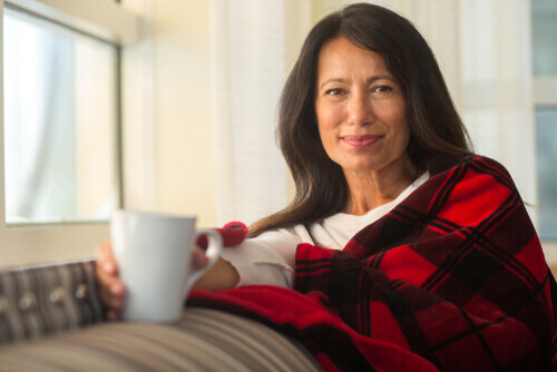 woman wrapped in cozy blanket with coffee