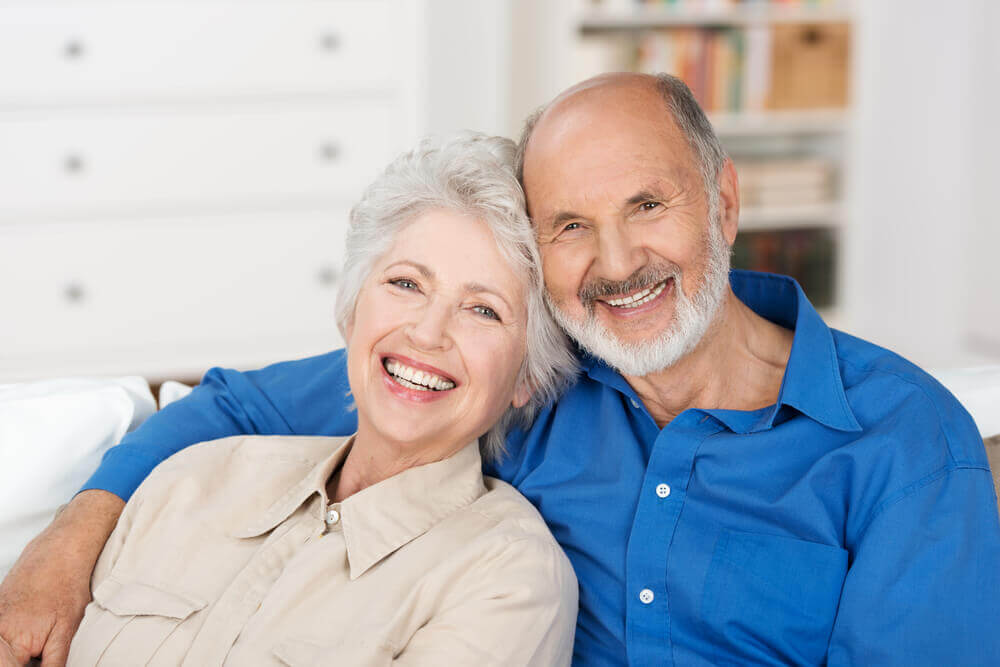 Mature couple smiling while sitting on couch